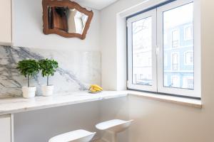 La salle de bains est pourvue de 2 chaises blanches et d'une fenêtre. dans l'établissement Embaixador Apartments&Suites, à Lisbonne