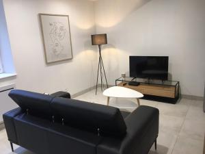 uma sala de estar com um sofá preto e uma televisão em Gîte Le Relais em Mer