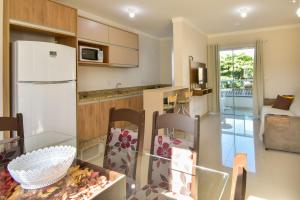 eine Küche mit einem Glastisch und einem weißen Kühlschrank in der Unterkunft Apartamento a 3 min do mar nos Ingleses Norte P154 in Florianópolis