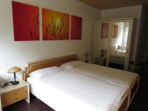 a bedroom with a white bed and a mirror at Hotel Pizzo Vogorno in Vogorno
