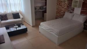 a bedroom with a bed and a couch and a chair at Atlantica Suites in Guarujá