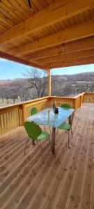 a wooden deck with a table and chairs on it at Căsuța de la luncă in Cireşu