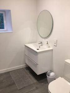 Baño blanco con lavabo y espejo en Gîte La Source, en Mer