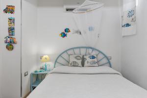 1 dormitorio con cama blanca y cabecero azul en Giglio apartment vista mare e parcheggio privato, en Porto Rotondo