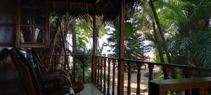 a room with a balcony with a chair and palm trees at Constantina Huts in Agonda
