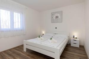 a white bedroom with a white bed and a window at Deluxe Apartment Stunning view in Jadranovo