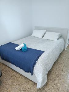 Cama blanca con manta azul y almohadas en Bonito estudio, Torremolinos, COSTA DEL SOL, en Torremolinos