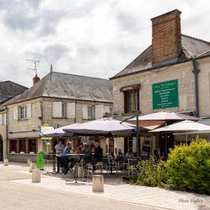 people sitting at tables with umbrellas in front of a building at Logis Auberge Le Colombien - Hôtel et Restaurant in Villandry