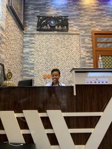 un hombre sentado en un mostrador en un restaurante en Zimbo Golden Vip Lodge, en Dar es Salaam
