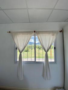 una ventana con cortinas blancas en una habitación en Departamento en La Punta en La Punta
