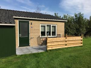a small house with a wooden fence in the yard at Bungalow op bedrijf met melkkoeien in De Cocksdorp