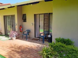 a patio with two chairs on a house at Chariots Guest House in Polokwane