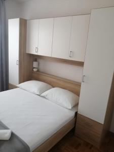 a bedroom with a white bed with white cabinets at Apartments Stipanovic in Biograd na Moru