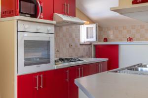 une cuisine rouge avec des appareils blancs et des armoires rouges dans l'établissement MERI, à Rab