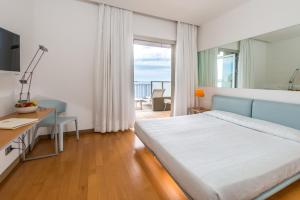 a bedroom with a bed and a desk and a window at Hotel Miramare - Adults Only in Trieste