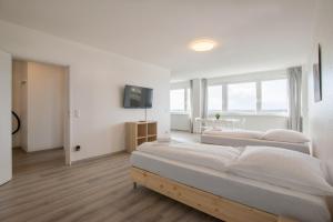 a white bedroom with two beds and a television at T&K Apartments Comfortable 3 Room Apartments with Balcony in Duisburg
