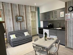 a kitchen and living room with a table and a couch at Le Clos des Marronniers in Douvres-la-Délivrande