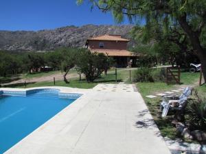 a swimming pool with a house in the background at Cabañas de Montaña San Miguel in Cortaderas