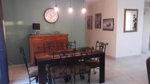 a dining room table with chairs and a clock on the wall at Maison meublée de la Varenne in Pannes