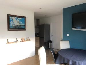comedor con mesa y TV en la pared en Logement neuf avec jardin privé 4 couchages Option piscine, en Les Iffs