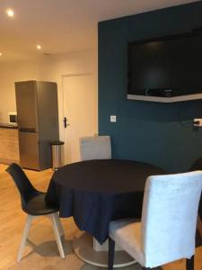 comedor con mesa, sillas y TV en Logement neuf avec jardin privé 4 couchages Option piscine, en Les Iffs