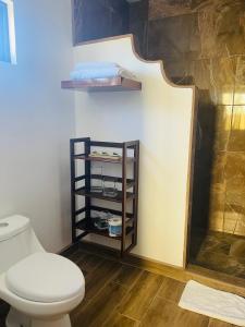 a bathroom with a toilet and a shelf with towels at Finca Chavez in Ensenada