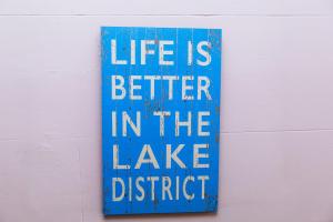 um sinal azul que diz que a vida é melhor no distrito do lago em Portland House em Keswick