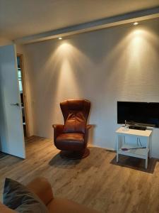 een woonkamer met een leren stoel en een tafel bij 'T Wolthoes in Vlagtwedde