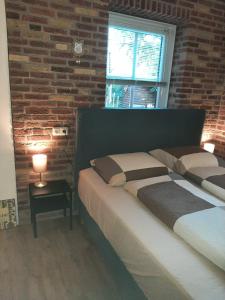um quarto com 2 camas e uma parede de tijolos em 'T Wolthoes em Vlagtwedde