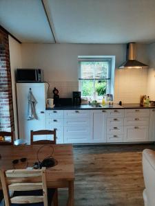 een keuken met witte kasten en een houten tafel bij 'T Wolthoes in Vlagtwedde