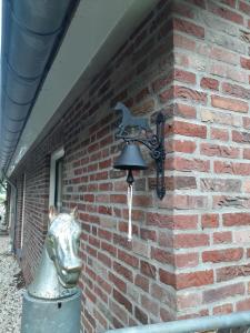 una campana con una cabeza de caballo en una pared de ladrillo en 'T Wolthoes, en Vlagtwedde