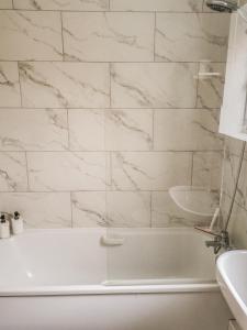 Baño blanco con bañera y lavamanos en Welcome Home, en Royston