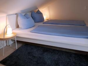 a large white bed with blue pillows and a table at House Seewind, Dornumersiel in Dornumersiel