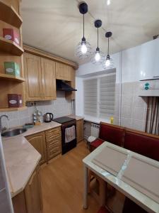 a kitchen with wooden cabinets and a table in it at Подобова оренда двокімнатної квартири Старичі in Starychi