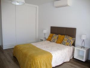 a bedroom with a large bed with a yellow blanket at Belinha Guest House in Luz