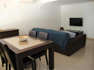 a living room with a couch and a table and a television at Belinha Guest House in Luz