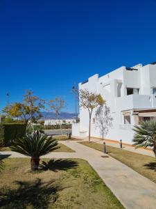 a white building with palm trees and a sidewalk at Condado de Alhama N478 in Alhama de Murcia