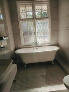 een badkamer met een wit bad en een raam bij Beautiful Villa - Scottburgh, Durban in Scottburgh