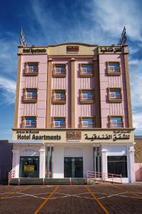 a large pink building with a hotel apartments at Arkan Al Barzah Hotel Apartment in Sur