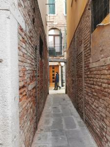 a man walking down an alley between two brick buildings at Pandora Flat with Altana in Venice