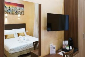 ローマにあるトリニティ ラグジュアリー ルームズのベッド1台、薄型テレビが備わるホテルルームです。