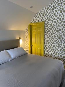 een slaapkamer met een bed en een gele deur bij The Archie & Isidore Hotel in Chéticamp