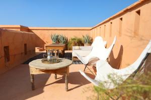 d'une terrasse avec des chaises blanches et une table sur un balcon. dans l'établissement Riad Azzouna 13, à Marrakech