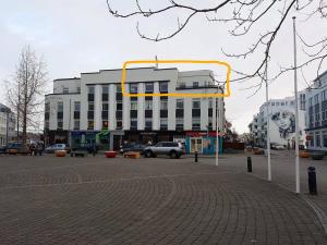 um grande edifício branco com uma moldura amarela numa rua em Lovely Penthouse downtown with 3 bedrooms em Akureyri