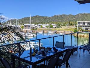a table on a balcony with a view of a marina at Blue on Blue Apartment 932 in Nelly Bay