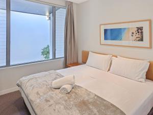 a bedroom with a large white bed with a window at Blue on Blue Apartment 932 in Nelly Bay