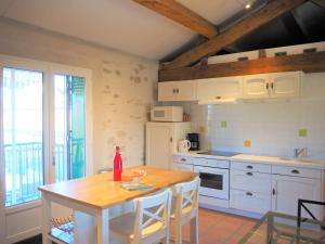 una cocina con armarios blancos y una mesa con una botella. en Holiday home, Villemagne-l'Argentière, en Villemagne