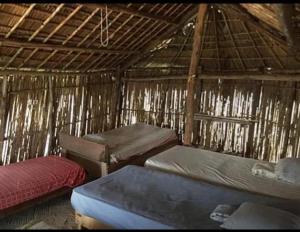 a room with three beds in a straw hut at Cabañas Tubasenika in Ailigandí