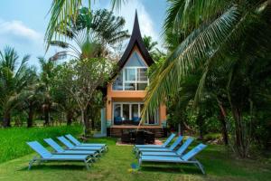 a group of blue lounge chairs in front of a house at vitamin sea villas in Ko Chang +61 photos