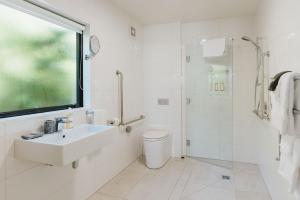 a white bathroom with a sink and a shower at Rimu Lodge in Hokitika